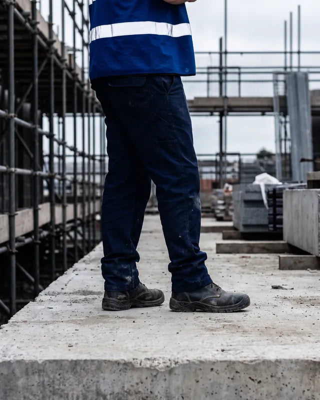 Ouvrier en gilet haute visibilité debout sur une dalle de béton
