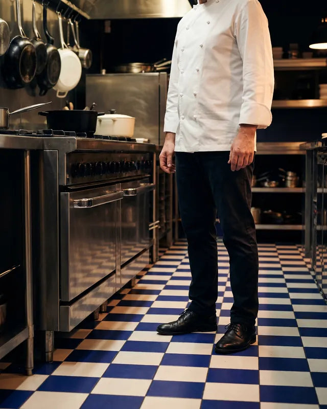 Cuisinier debout sur le carrelage d'une cuisine professionnelle